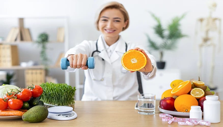 Female nutritionist holding dumbbell and orange promoting healthy lifestyle with fresh fruits, vegetables, water and fitness wellness.